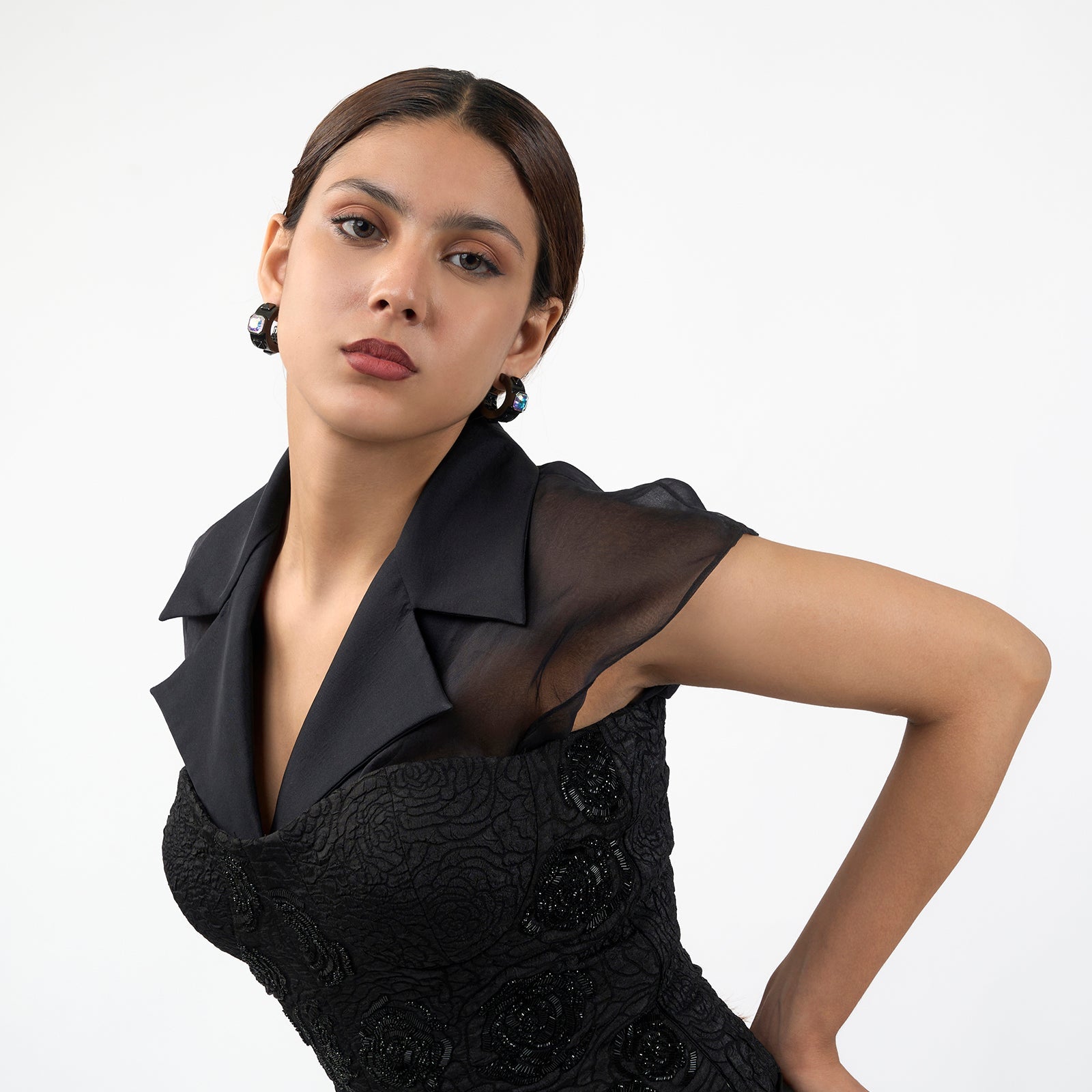 Woman wearing a black dress with sheer overlay on a white background